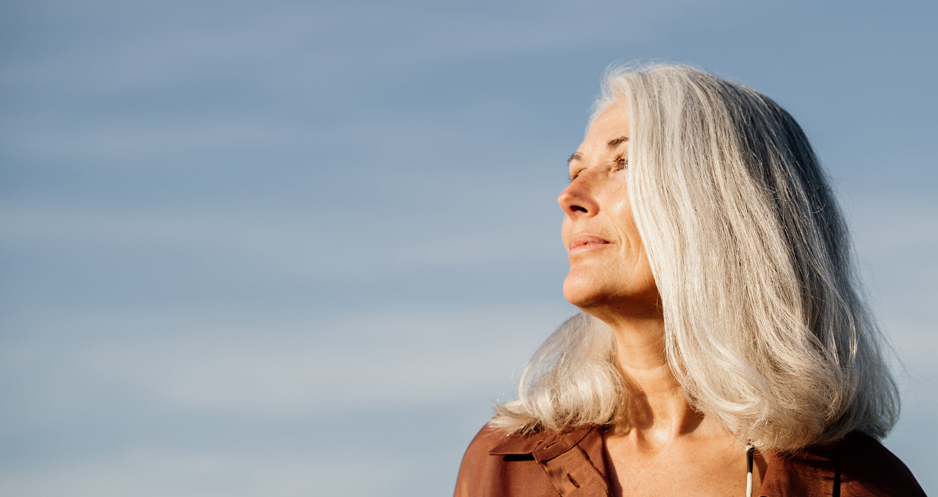 Frau Anfang 50 lächelnd im Morgenlicht – Perimenopause & Wohlbefinden